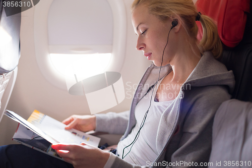 Image of Woman reading magazine on airplane.