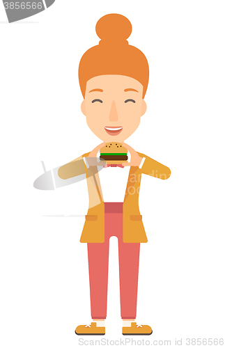 Image of Woman eating hamburger. 