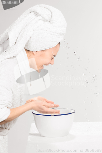 Image of Woman cleaning face in bathroom