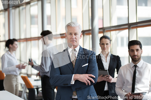 Image of portrait of senior businessman as leader  with group of people i