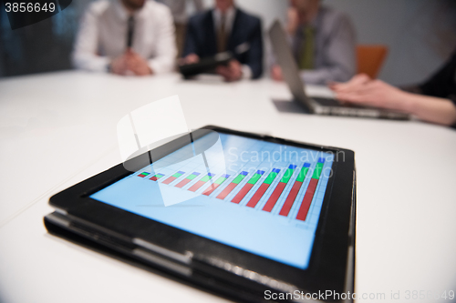 Image of close up of touchpad with analytics documents at business meetin