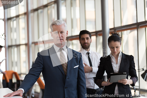 Image of portrait of senior businessman as leader  with group of people i