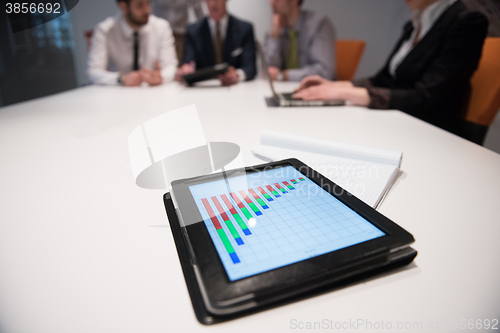 Image of close up of touchpad with analytics documents at business meetin