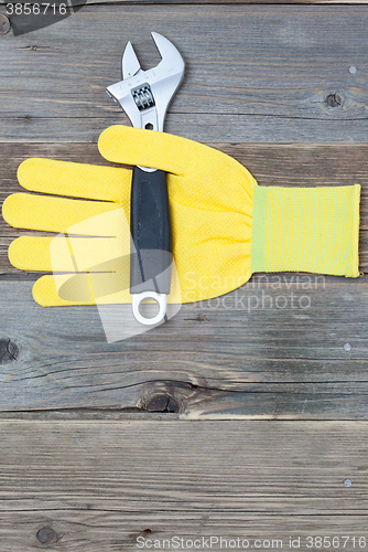 Image of yellow safety glove and a pipe wrench