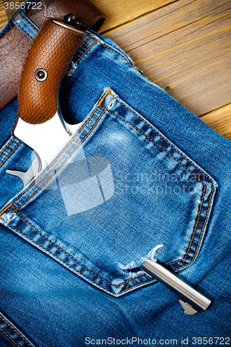 Image of silver revolver nagant with brown handle in the pocket