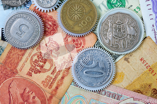 Image of coin gear on the background of banknotes