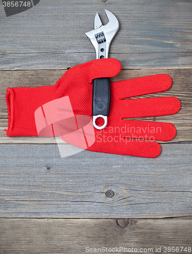 Image of red glove and a pipe wrench