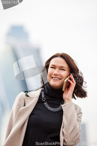 Image of business woman in a bright coat talking on a cell phone