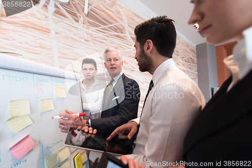 Image of business people group brainstorming and taking notes to flipboar