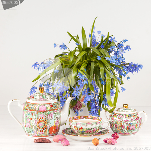 Image of Tea with  lemon and bouquet of  blue primroses on the table