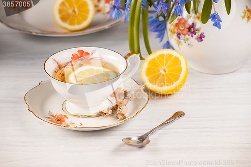 Image of Tea with  lemon and bouquet of  blue primroses on the table