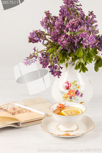 Image of Tea with  lemon and bouquet of  lilac primroses on the table