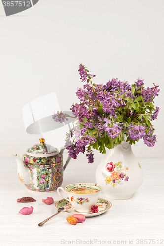 Image of Tea with  lemon and bouquet of  lilac primroses on the table