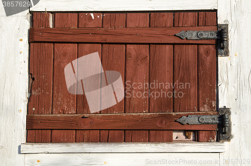 Image of Weathered red plank window shutter
