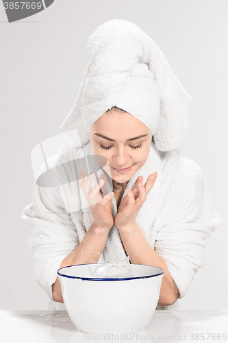 Image of Young woman washing face with clean water