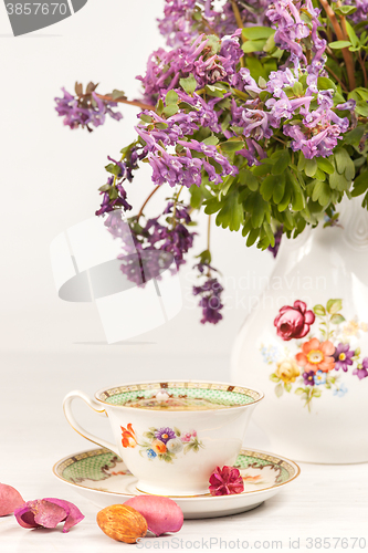 Image of Tea with  lemon and bouquet of  lilac primroses on the table