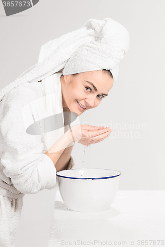 Image of Young woman washing face with clean water