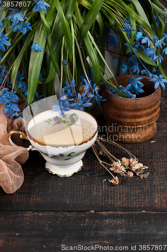 Image of Tea with  lemon and bouquet of  blue primroses on the table