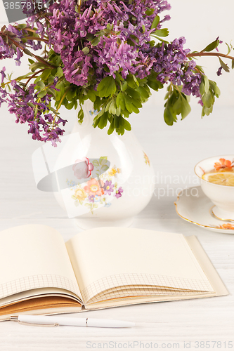 Image of Tea with  lemon and bouquet of  lilac primroses on the table