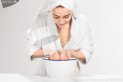Image of Young woman washing face with clean water