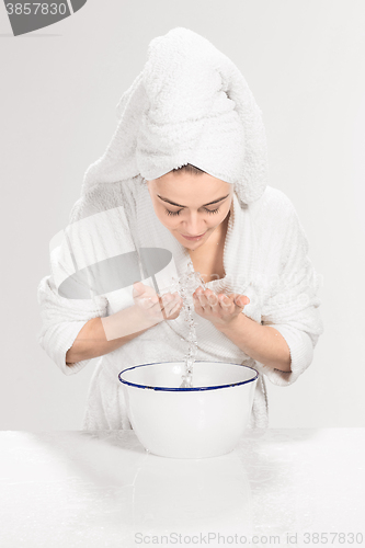 Image of Young woman washing face with clean water