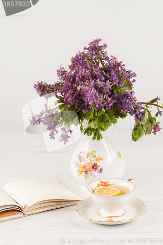 Image of Tea with  lemon and bouquet of  lilac primroses on the table