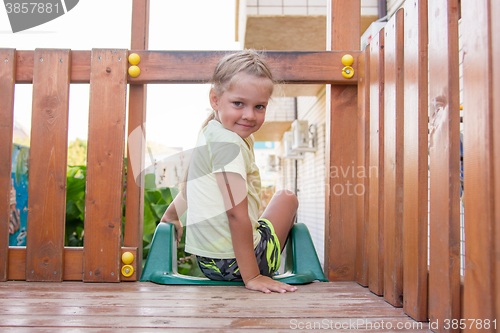 Image of Four-year girl sitting on a wooden platform personal game complex