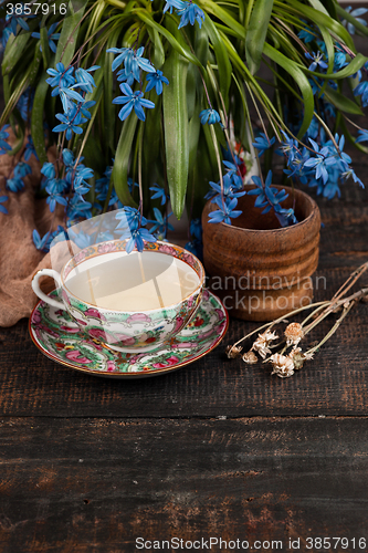 Image of Tea with  lemon and bouquet of  blue primroses on the table