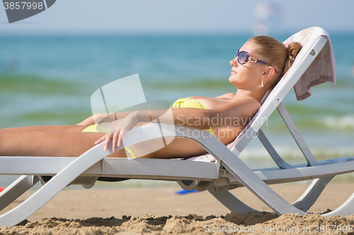 Image of Young tanned woman lying relaxed on a sun lounger on the beach