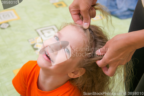 Image of  four years old girl laughs as she braided long hair