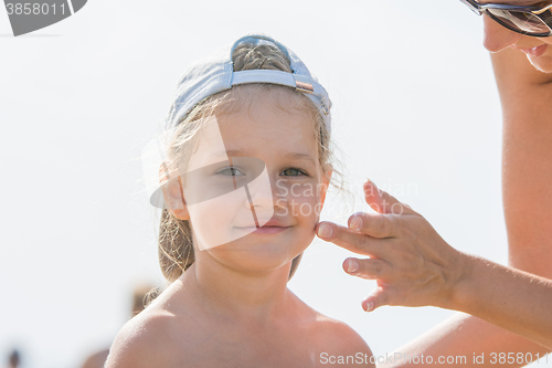 Image of Mom rubs sunscreen face pretty child