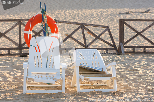 Image of Two old beach chairs stand near the lifeline on the sandy beach