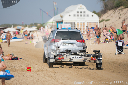 Image of Anapa, Russia - September 20, 2015: passenger car with a trailer, riding on the beach with holidaymakers