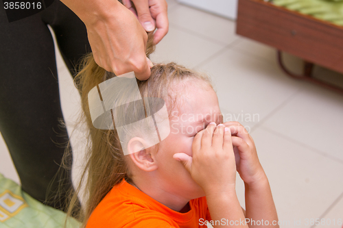 Image of The little girl was crying when she braided long hair