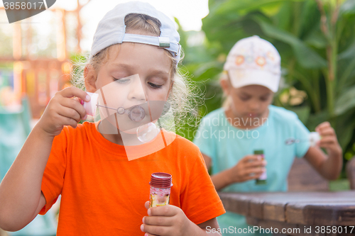 Image of Little girls enthusiastically inflated bubbles in the street