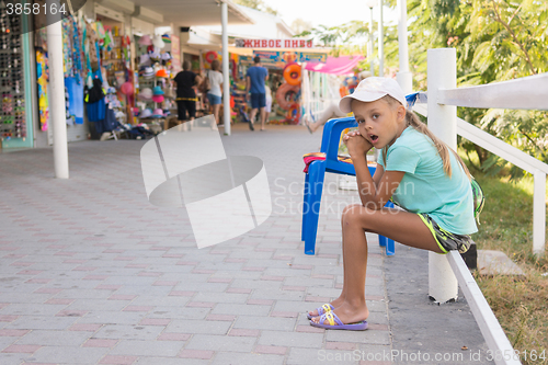 Image of Tired girl yawning six years sat in front of stalls