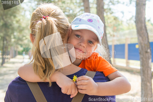 Image of Pretty little girl is looking through my mothers shoulder while sitting in her arms