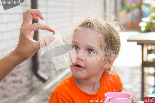 Image of Four-year girl showing a pea, which she treats with great interest