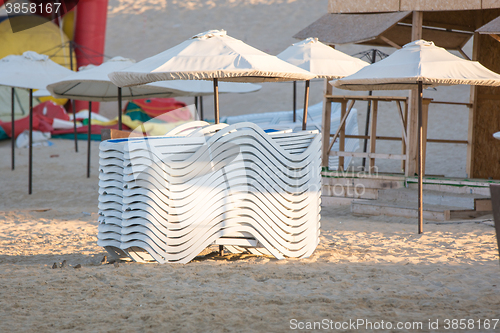 Image of Stacked chairs in the evening on the beach under the umbrellas