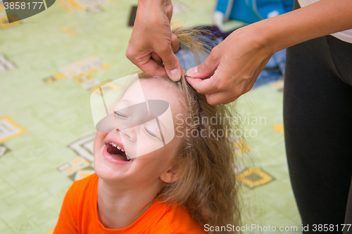 Image of A girl of four years old sitting happily when she do her hair