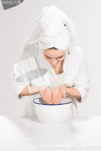 Image of Young woman washing face with clean water