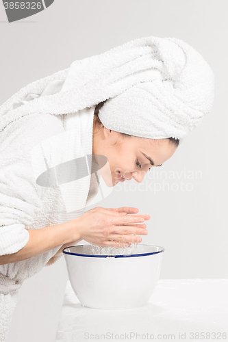 Image of Young woman washing face with clean water