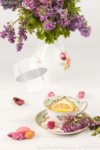 Image of Tea with  lemon and bouquet of  lilac primroses on the table