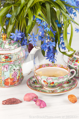 Image of Tea with  lemon and bouquet of  blue primroses on the table