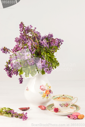 Image of Tea with  lemon and bouquet of  lilac primroses on the table