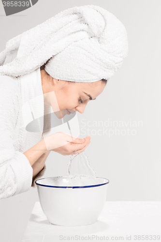 Image of Young woman washing face with clean water