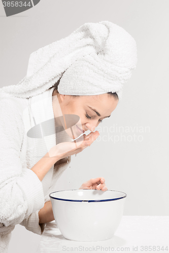 Image of Young woman washing face with clean water