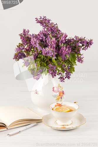 Image of Tea with  lemon and bouquet of  lilac primroses on the table