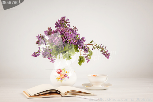 Image of Tea with  lemon and bouquet of  lilac primroses on the table