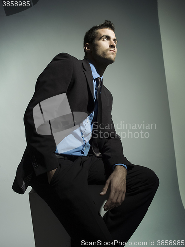 Image of elegant fashionable man with black suit in grey background